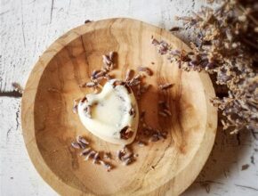 Badepraline auf einer Holzschale mit getrocknetem Lavendel