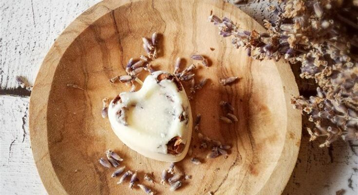 Badepraline auf einer Holzschale mit getrocknetem Lavendel