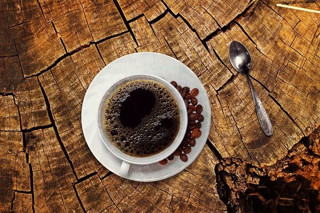 Tasse Kaffee mit Kaffeebohnen auf einem Stück Holz