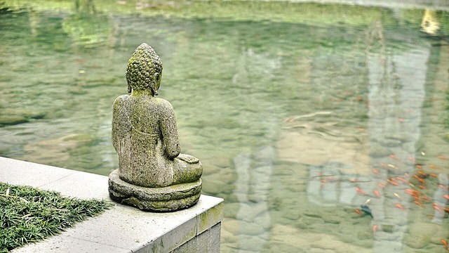 Eine steinerne Buddha-Figur an einem Teich.