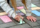 Ein Kind malt mit bunter Straßenkreide