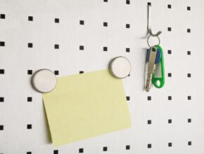 Ein Pegboard mit einem Schlüssel und einer Haftnotiz mit Magneten daran.
