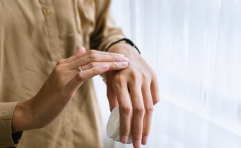 Jemand, der sich seine Hände mit einer Creme eincremt; in der einen Hand den Tiegel.